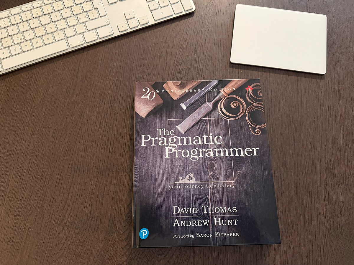 The Pragmatic Programmer book on a table with a keyboard and a mouse pad.